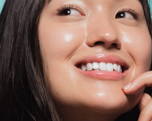 Close up of cute asian girl with glowing skin against blue background. Beautiful face of girl with fresh healthy skin.