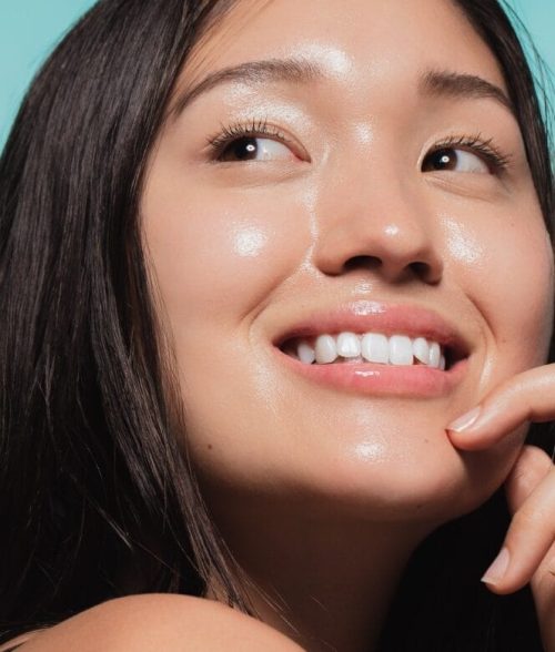 Close up of cute asian girl with glowing skin against blue background. Beautiful face of girl with fresh healthy skin.