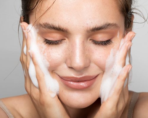 Close up studio shot of a beautiful woman with perfect skin, while she cleaning her face