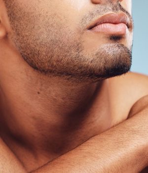 Man, jaw and skincare, face grooming and beard for beauty, aesthetic wellness and healthy skin on studio blue background. Closeup of handsome guy model, facial hair and dermatology body cosmetics